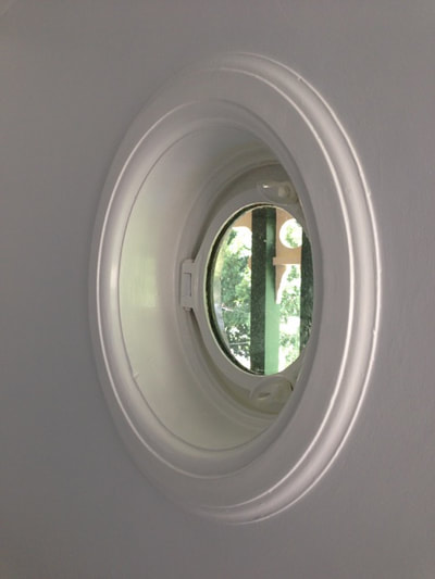 A beautiful painted window that is an actual ships porthole.